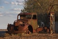 Abandoned rusty old pick up truck wreck sits derelict on the side of a road on sunset