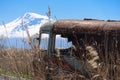 Abandoned and rusty old Soviet Russian bus in the middle of reeds and agriculture fields with Mt. Ararat on the background