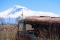 Abandoned and rusty old Soviet Russian bus in the middle of reeds and agriculture fields with Mt. Ararat on the background