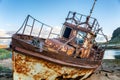 An abandoned rusty ship on a sandy beach and a backdrop of mount