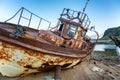 An abandoned rusty ship on a sandy beach and a backdrop of mount