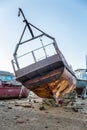 An abandoned rusty ship on a sandy beach and a backdrop of mount