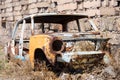 Abandoned and rusty skeleton of a Soviet Russian car by the side of the building exterior