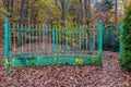 Abandoned and rusty wrought iron gate green with yellow, abundant trees with yellowish-green foliage Royalty Free Stock Photo