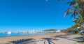 Abandoned sailboat on the beach. Rows of palm trees line water`s edge in Ibiza, St Antoni de Portmany Balearic Islands, Spain.