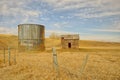 Abandoned Shed and Grain Silo Behind a Barbed Wire Fence in Spring