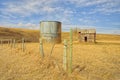 Abandoned Shed and Grain Silo Behind a Barbed Wire Fence in Spring