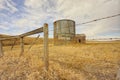 Abandoned Shed and Grain Silo Behind a Barbed Wire Fence in Spring