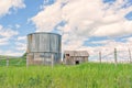 Abandoned Shed and Grain Silo Behind a Barbed Wire Fence in Summer