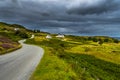 Abandoned Single Track Road Through Scenic Hills With Houses At The Coast Of The Isle Of Skye In Scotland