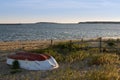 Abandoned small fishing boat on beach at sunset