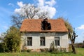 Abandoned small suburban family house ruins with large hole in middle of destroyed roof and cracked facade