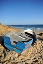 Abandoned small wooden boat -patera- on a beach near Tarifa, coast of Andalusia, Spain.