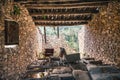 Abandoned stone house with wooden roof and broken wall with outside view. Ruin of ancient deserted building with old