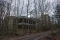 An abandoned structure is nestled amidst overgrown vegetation and leafless trees