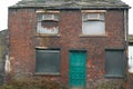 abandoned old terrace house with blue door and rotted window frames