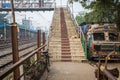 An abandoned truck stands beside a manual overbridge at a railway station