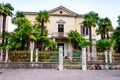Abandoned two floors classical Italian house with growing palm in the garden metal fence and gate at the entrance in Riva del