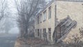 An abandoned two-story wooden house by the road on a foggy day Royalty Free Stock Photo