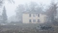 An abandoned two-story wooden house by the road on a foggy day Royalty Free Stock Photo