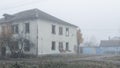 An abandoned two-story wooden house by the road on a foggy day Royalty Free Stock Photo