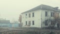 An abandoned two-story wooden house by the road on a foggy day Royalty Free Stock Photo