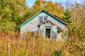 Abandoned urban single room home with crocked front portal door in thick overgrown forest field Royalty Free Stock Photo