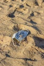 Abandoned used face mask on the beach with outdoor sun lighting Royalty Free Stock Photo