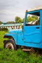 Abandoned vintage car blue lush green grass in college campus