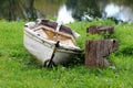 Abandoned vintage rustic old fiberglass river boat left on local river bank next to tree stumps cut to resemble smiling face Royalty Free Stock Photo