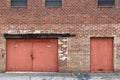 Abandoned warehouse alley brick wall red doors Royalty Free Stock Photo