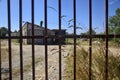 Abandoned warehouse behind a closed gate on a sunny day in the countryside Royalty Free Stock Photo