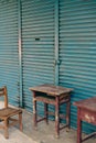 Abandoned wooden desk and chair in front of blue shutter door in Taiwan Royalty Free Stock Photo