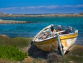 abandoned wooden fish boat at the shore. The boat is destroyed and rusty an completely useless with the sea and the blue sky at Royalty Free Stock Photo