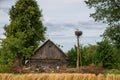 Abandoned wooden house in russian village and stork in nest on pillar. Rural landscape Royalty Free Stock Photo