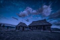 Abandoned wooden houses on a hill under the night starry sky Royalty Free Stock Photo