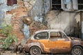 Abandoned wrecked orange vintage car against old brick wall