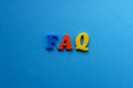 Abbreviation FAQ from plastic magnetic letters on blue background Royalty Free Stock Photo