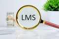 Abbreviation of Learning management system, Word LMS writing through a magnifying glass on a light background near a roll of money