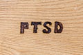 An abbreviation PTSD - post traumatic stress disorder - burned by hand on flat wooden board