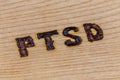 An abbreviation PTSD - post traumatic stress disorder - burned by hand on flat wooden board in diagonal composition