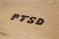 An abbreviation PTSD - post traumatic stress disorder - burned by hand on flat wooden board in diagonal composition