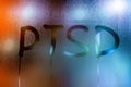 An abbreviation PTSD - post traumatic stress disorder - handwritten on wet glass of night window Royalty Free Stock Photo