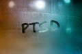 an abbreviation PTSD - post traumatic stress disorder - handwritten on wet glass of night window