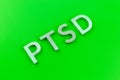 Abbreviation PTSD - post traumatic stress disorder - laid with silver metal letters on acid green flat surface