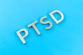 Abbreviation PTSD - post traumatic stress disorder - laid with silver metal letters on blue flat surface