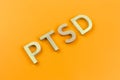 Abbreviation PTSD - post traumatic stress disorder - laid with silver metal letters on yellow flat surface