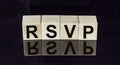 Abbreviation rsvp request for a response from an invited person in wooden blocks on a black mirrored background