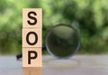 The abbreviation SOP is a standard operating procedure on wooden cubes on a table with a magnifying glass Royalty Free Stock Photo