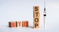 The abbreviation STD STOP formed by wooden blocks on a white table. Next to it is a syringe - a threat to life, a medical concept Royalty Free Stock Photo